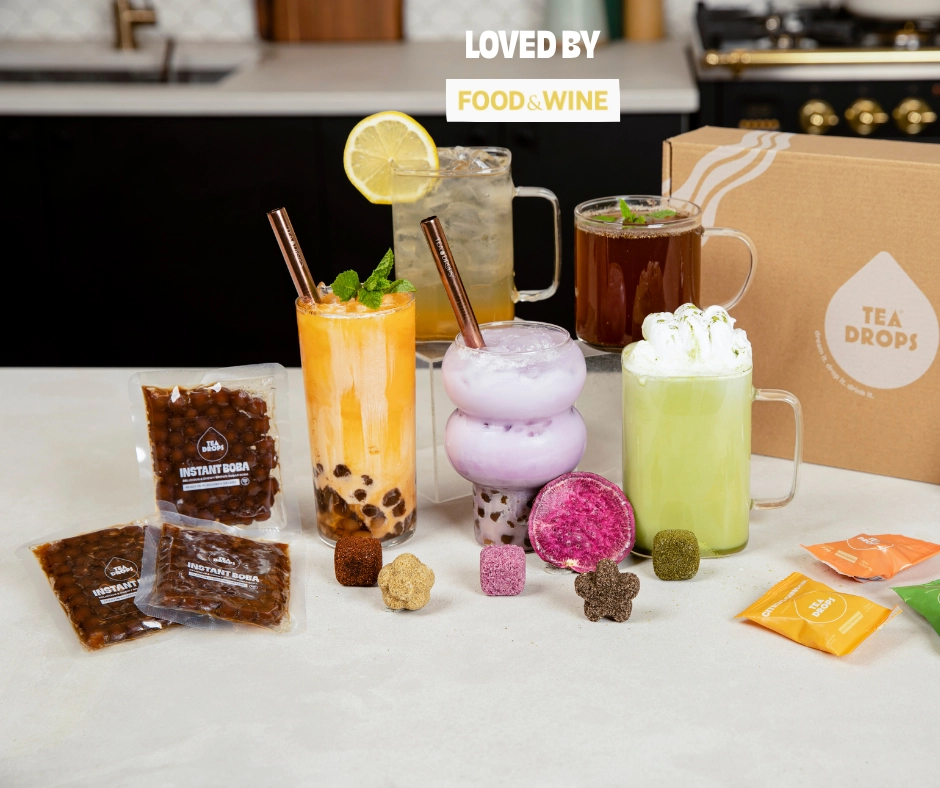 Iced teas, a boba tea and a matcha latte with Tea Drops and instant boba on a counter