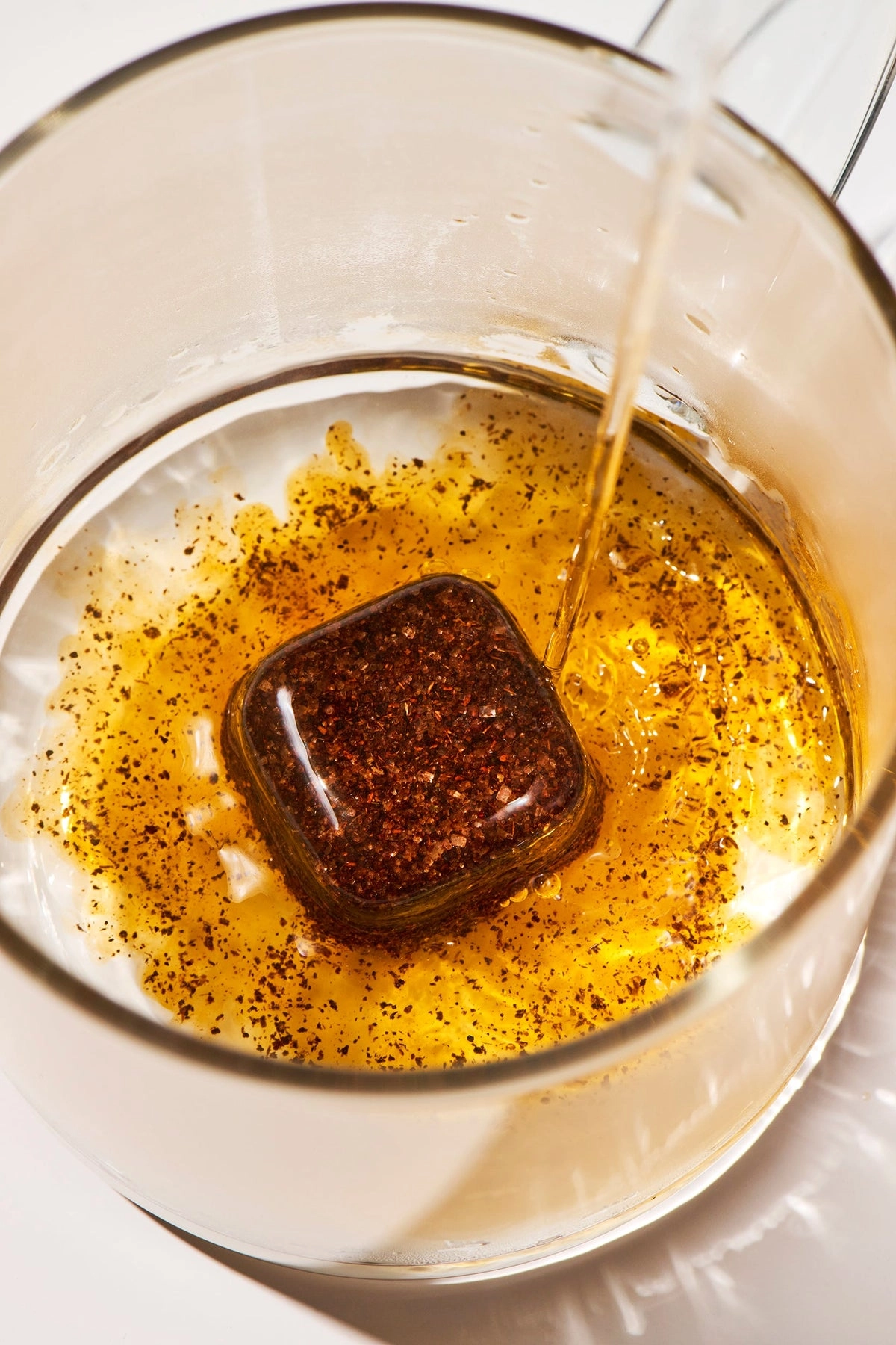 A Tea Drop dissolving in a glass of amber tea